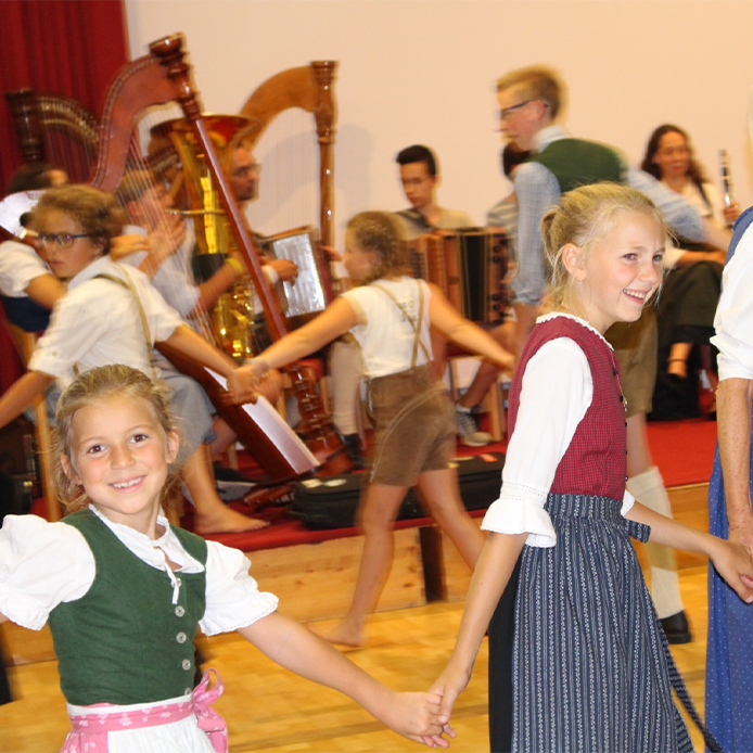 zwei Mädchen in Dirndlkleidern, zu Volksmusik tanzend