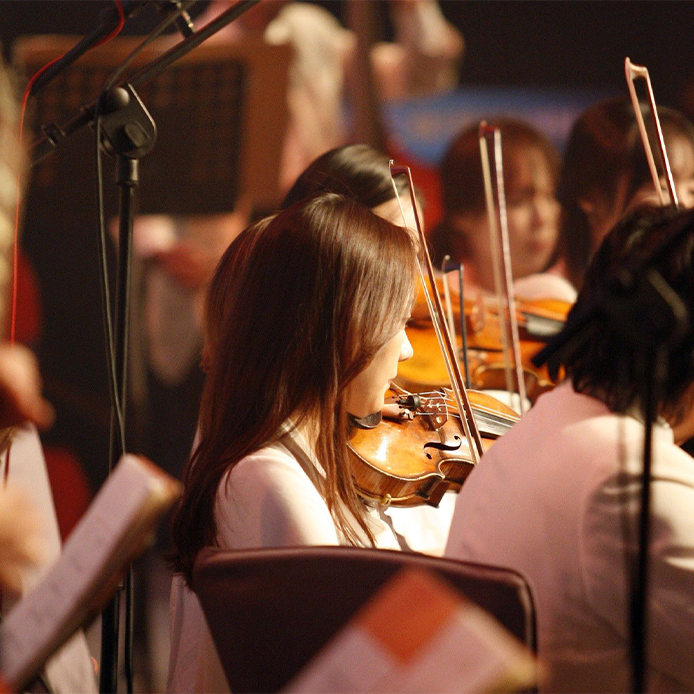 Nahaufnahme eines Geige spielenden Mädchens inmitten eines Orchesters