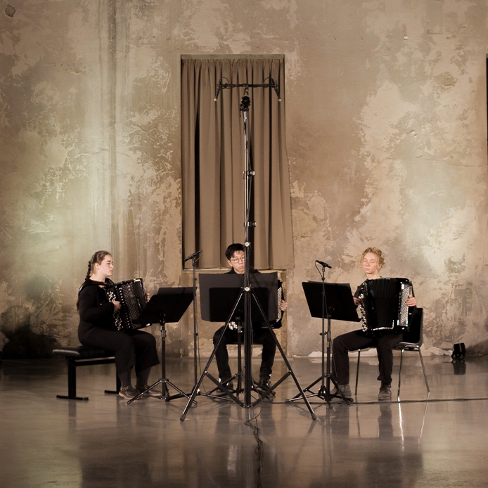 Akkordeon-Trio beim Auftritt in einer großen, ausladenden Konzerthalle