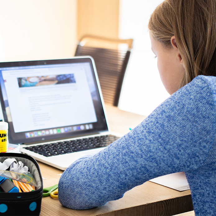 Mädchen vor dem Laptop sitzend und lernend