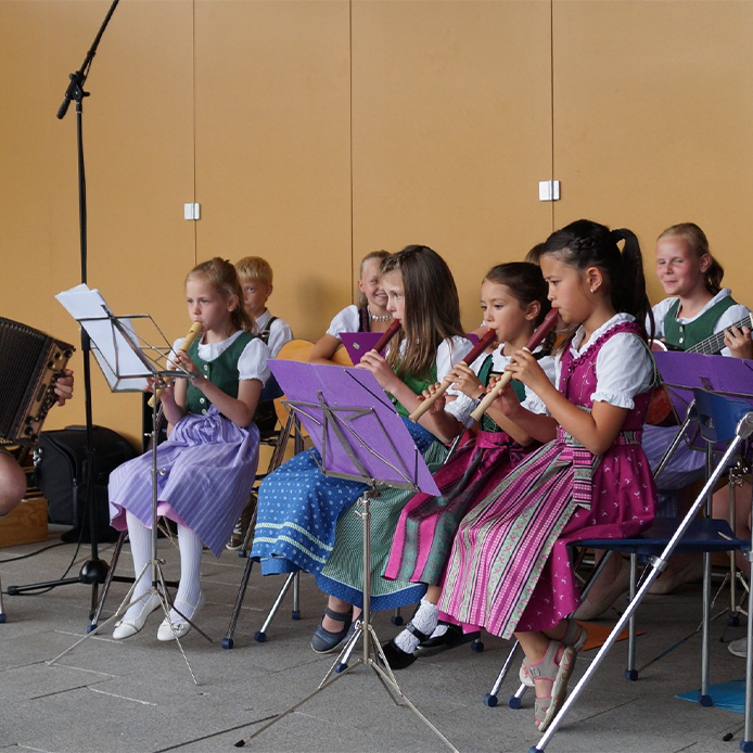 Musizierende Kinder mit Blockflöten und Harmonikas in Tracht auf der Bühne