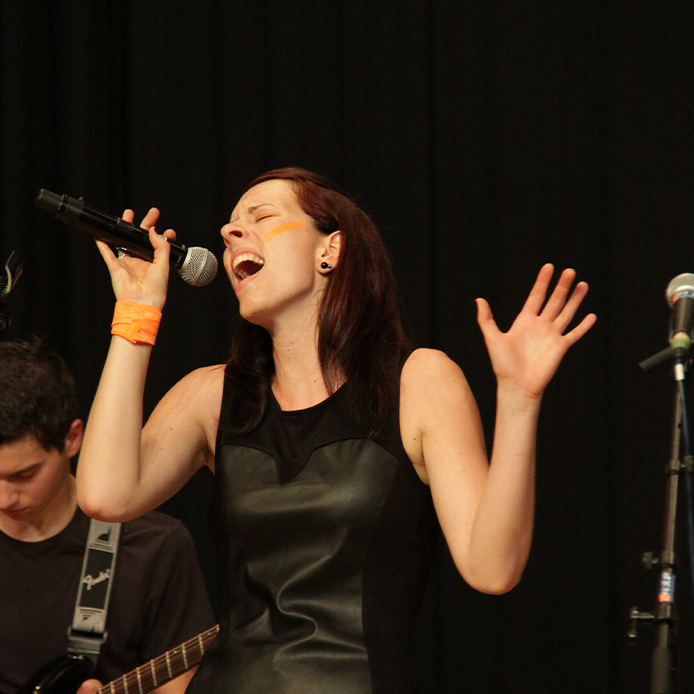 Mädchen auf der Bühne singend mit Mikrophon in der Hand