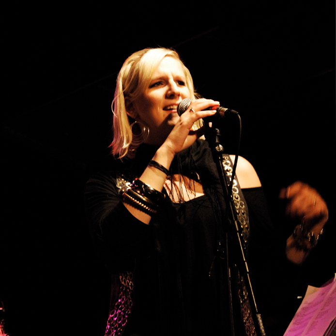 Sängerin mit Mikrophon auf der Bühne, schwarzer Hintergrund