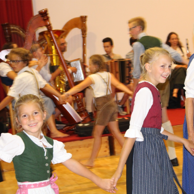 zwei Mädchen in Dirndlkleidern, zu Volksmusik tanzend