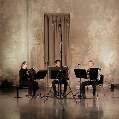 Akkordeon-Trio beim Auftritt in einer großen, ausladenden Konzerthalle