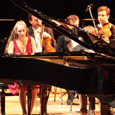 Pianistin am Konzertflügel vor einem Orchester