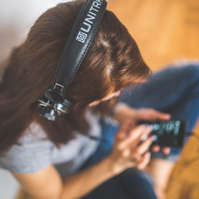 Frau mit Kopfhörern, die über das Handy Musik abspielt