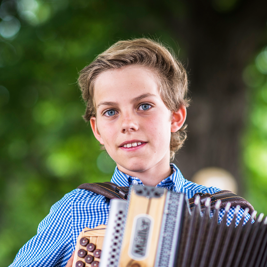Blauäugiger Junge mit einer Steirischen Harmonika, der direkt in die Kamera blickt| © Daniela Matejschek / MKM NÖ